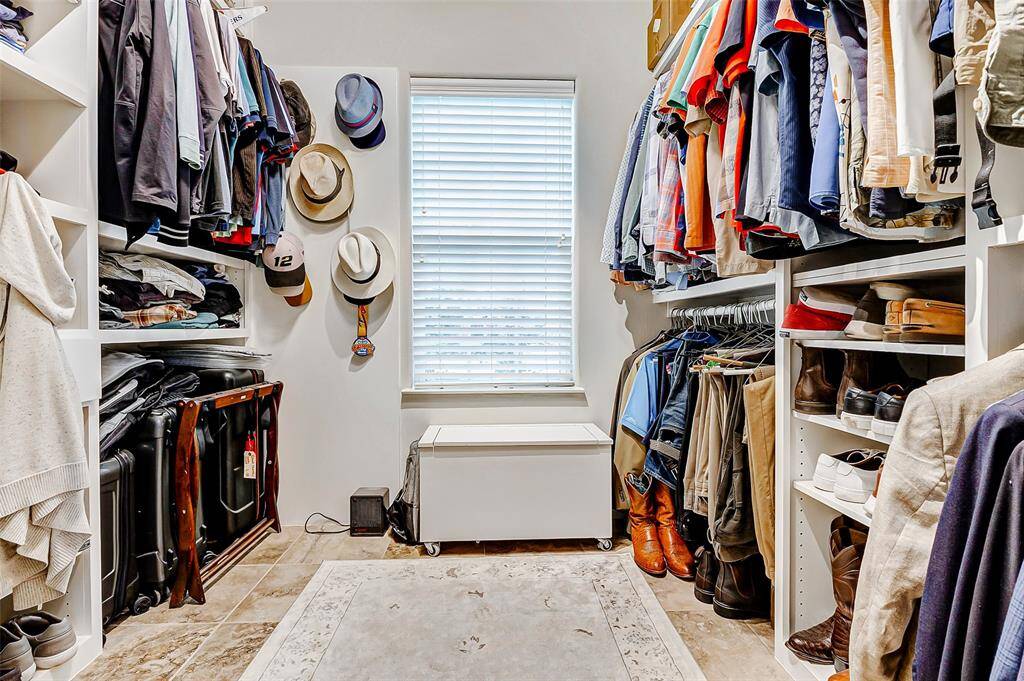 This spacious walk-in closet features ample shelving and hanging space for clothing, hats, and shoes.