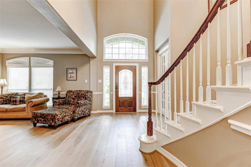 This inviting entryway features a high ceiling and abundant natural light. The formal living area welcomes you as you come in the front door with new wood flooring creating a welcoming atmosphere.