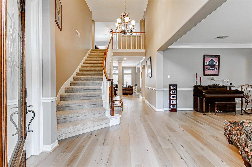 This welcoming entryway features a carpeted staircase with a wooden handrail, leading up to a bright, open second floor.