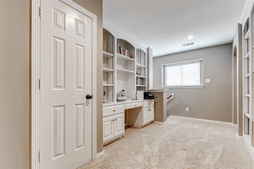 Elevate your productivity in this upstairs home office featuring built-in shelving and a dedicated desk area.