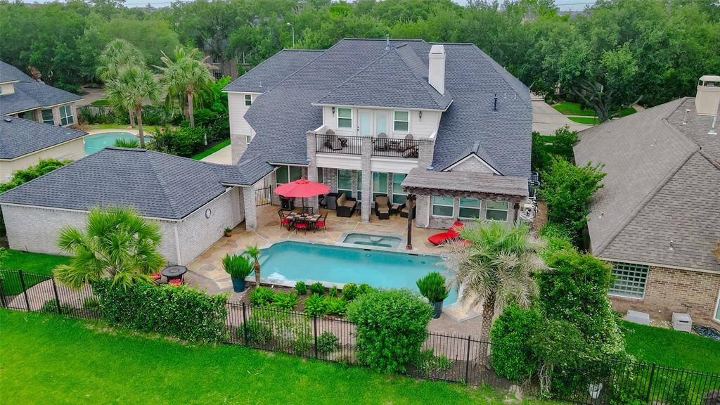 The backyard is surrounded by lush greenery and beautiful landscaping around the pool.