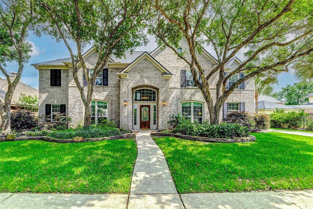 Beautiful curb appeal with mature trees and landscaped lawn.