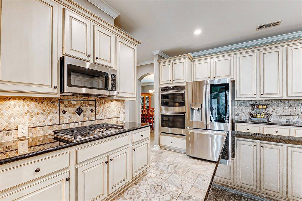Modern kitchen with stainless steel appliances, gas cooktop, and double oven.