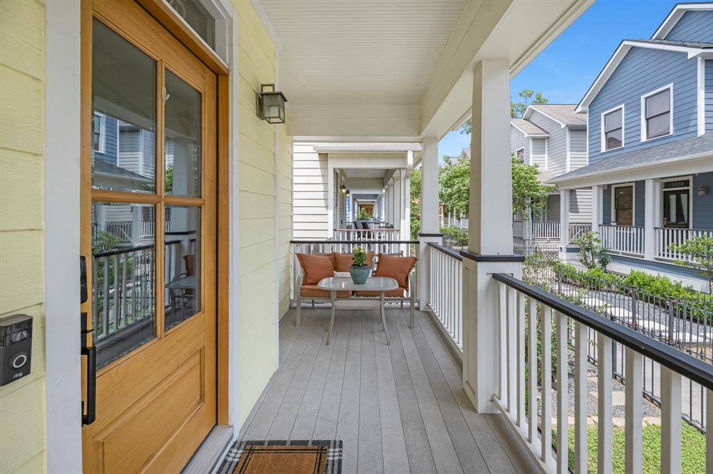 Lovely covered front porch features synthetic decking for low maintenance