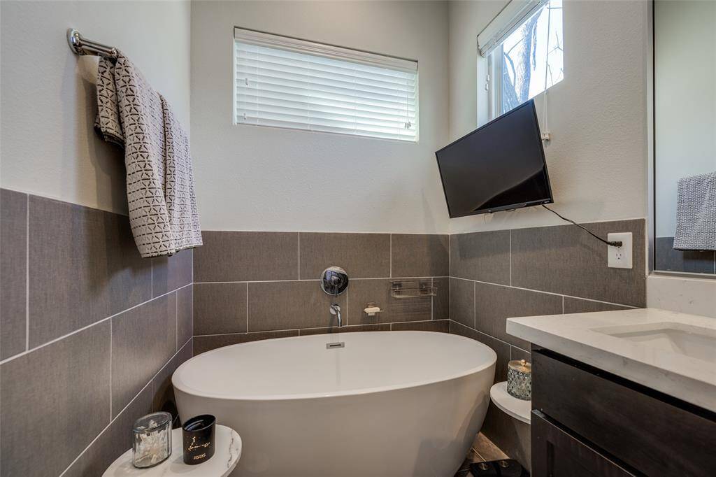 Gorgeous Primary Bathroom with stand alone tube, gray tile floor & shower, beautiful mahogany cabinets, 2 sinks , los of natural light & high ceilings