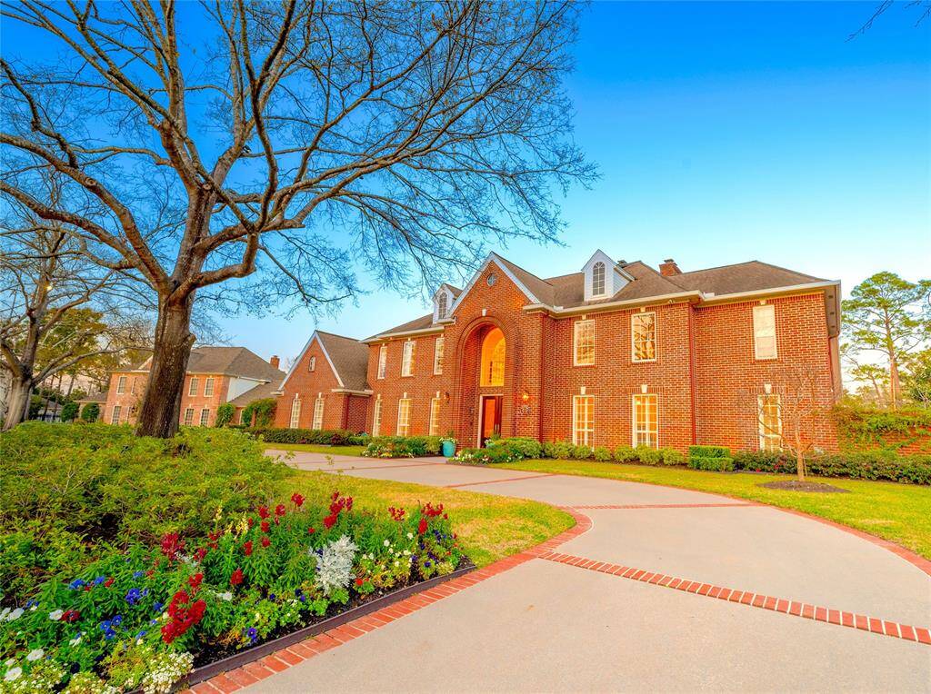 Stately brick estate with a grand entry, circular driveway, and elegant landscaping in a prestigious neighborhood