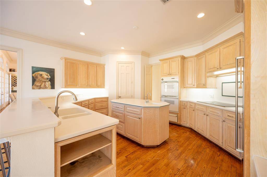 This spacious and inviting kitchen features custom wood cabinetry, sleek countertops, and a central island, all beautifully illuminated by recessed lighting.