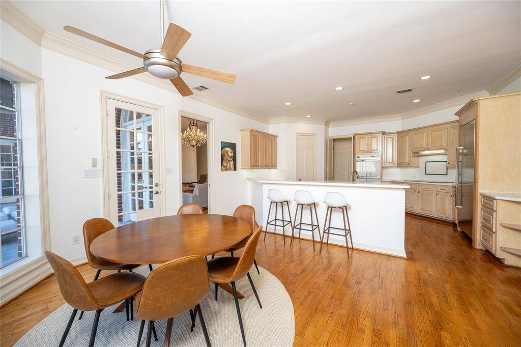 This elegant open-concept kitchen and dining area showcases rich hardwood flooring, a stylish round dining set, and a spacious chef’s kitchen with custom cabinetry, high-end appliances.