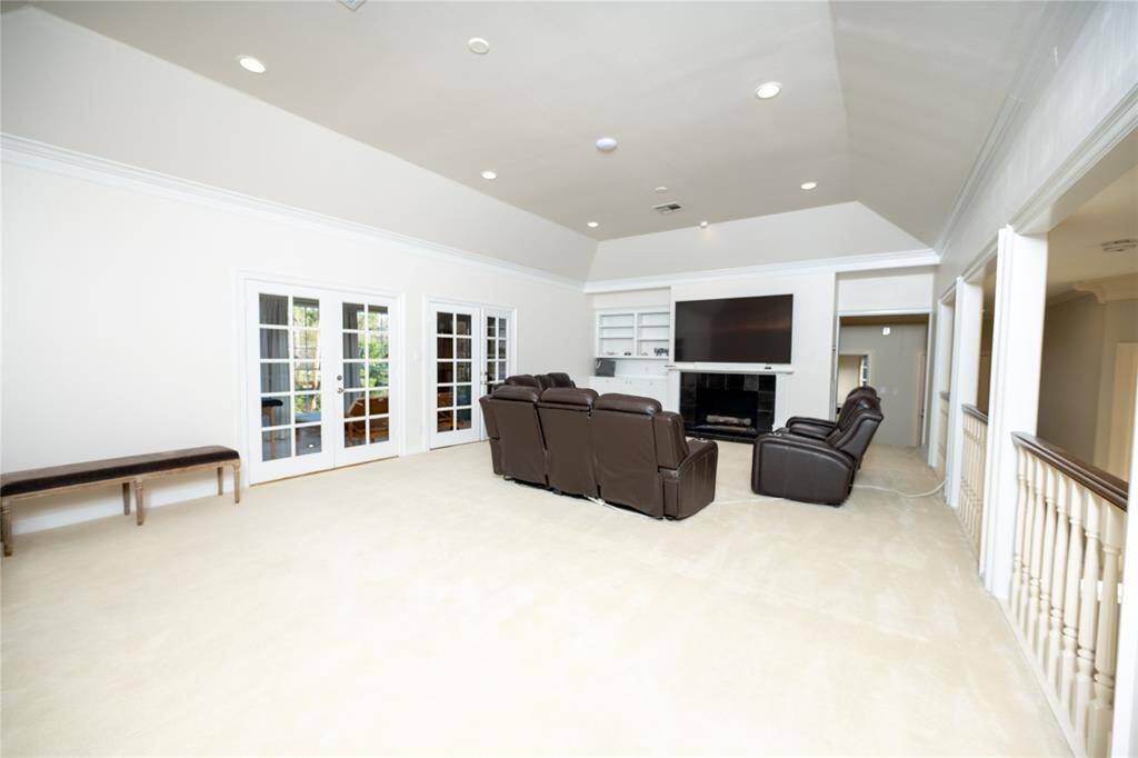 This expansive game room boasts soaring ceilings, recessed lighting, and large walls that enhance the spacious feel, while the open layout provides the perfect setting for entertainment.