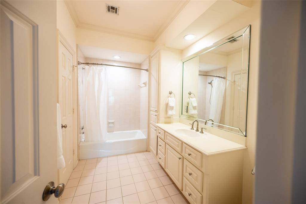 This beautifully appointed bathroom boasts a spacious vanity with ample storage, soft recessed lighting, and a pristine tub-shower combination.
