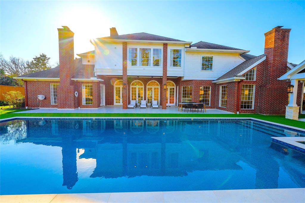 This exquisite backyard is a private oasis, featuring a resort-style pool, lush landscaping, and a spacious covered patio perfect for elegant outdoor entertaining and relaxation.