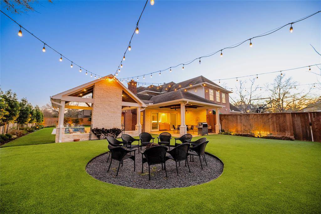 Experience the ultimate backyard retreat featuring a beautifully illuminated outdoor living space with elegant string lights, a spacious seating area centered around a stylish fire pit, and a well-manicured lawn. The private, fully fenced yard offers a perfect blend of comfort and entertainment, complemented by a covered patio ideal for outdoor gatherings.