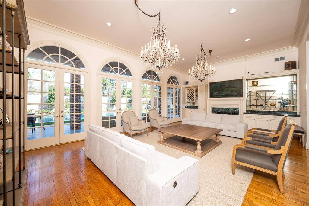 This stunning living room boasts elegant glass mirrors that enhance the sense of space and light, complementing the sophisticated chandeliers, arched windows, and timeless.