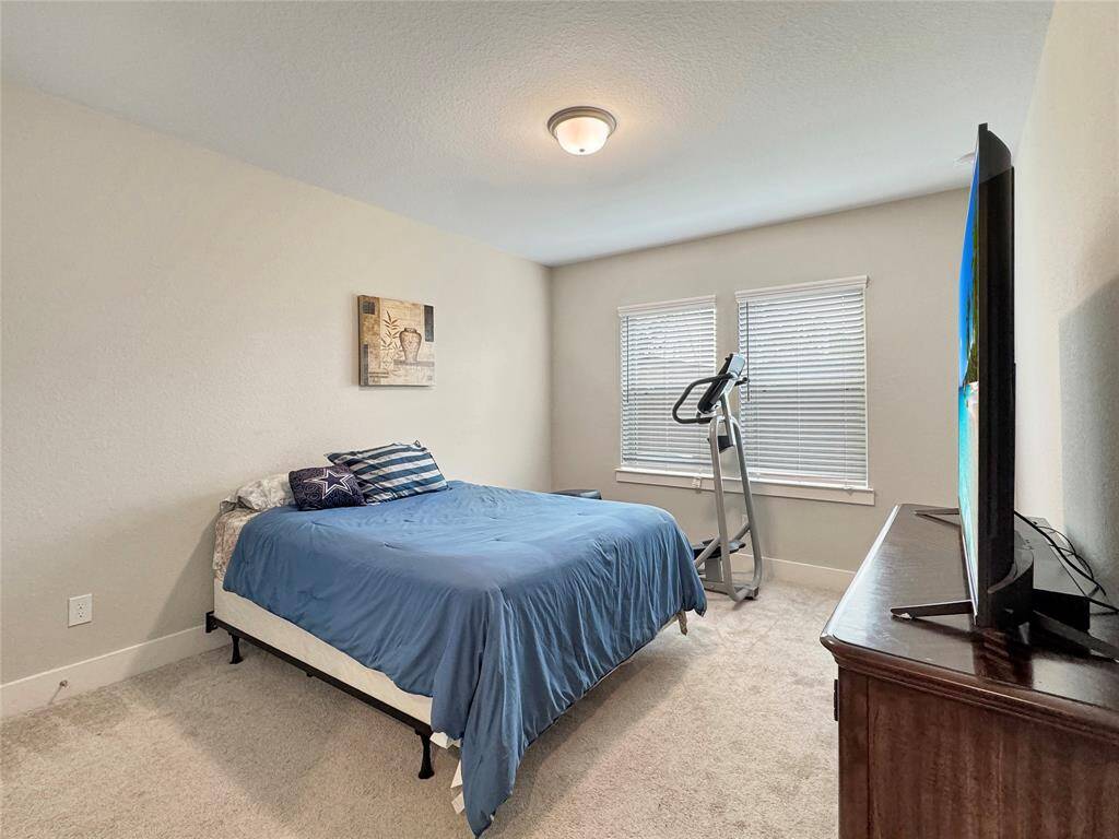 Cozy second bedroom with neutral walls and carpet, featuring two windows that overlook the patio and provide natural light.