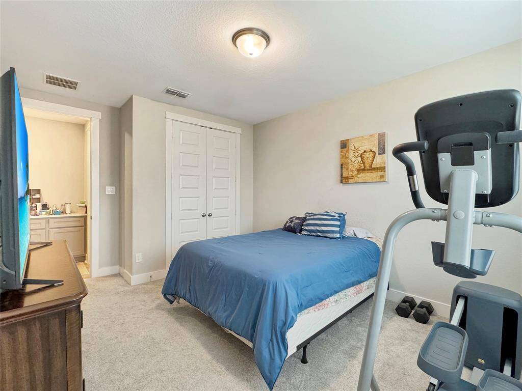 Cozy second bedroom with neutral walls and carpet, featuring two windows that overlook the patio and provide natural light.