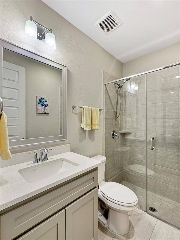 Modern secondary bathroom featuring a glass-enclosed shower, sleek vanity with a white countertop, and contemporary fixtures. It has neutral color tiles and lighting, providing a clean and bright atmosphere.