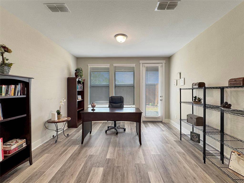 Bright home office with large windows and a glass door for natural light coming from the patio.