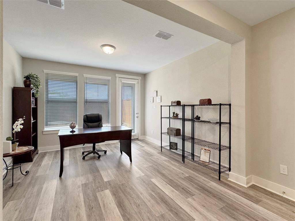 Bright home office with large windows and a glass door for natural light coming from the patio.