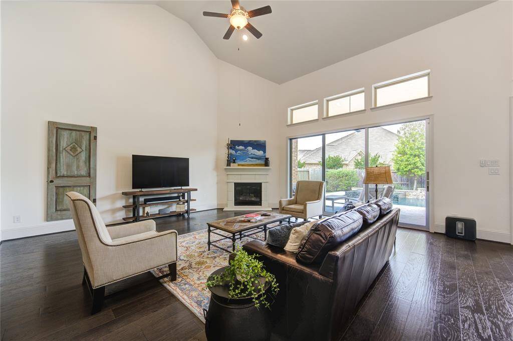 Experience the perfect blend of comfort and elegance in this expansive family room, featuring soaring ceilings, a cozy fireplace, and sliding glass doors that flood the space with natural light, offering stunning views of the pool and patio.