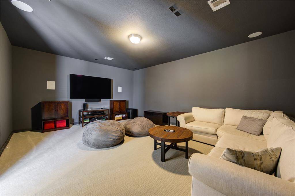 Cozy media room with dark walls and plush carpet are perfect for intimate movie nights.