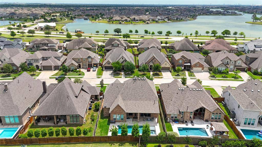 This photo showcases a beautiful suburban neighborhood with spacious, modern homes featuring large backyards, some with pools. The area is well-maintained with tree-lined streets and is situated near a scenic lake, offering a serene and picturesque setting.
