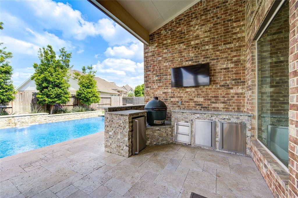 The extended back patio has an outdoor kitchen, sun shades and ample seating.