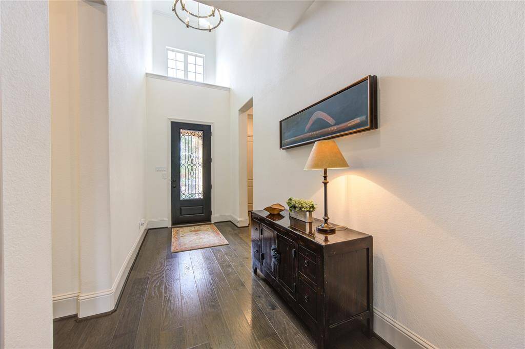 Bright and inviting entryway with high ceilings, natural light and a stylish door with wrought iron detailing.