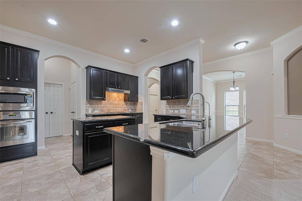 Functional kitchen with stainless steel appliances, large sink, granite countertops, natural light