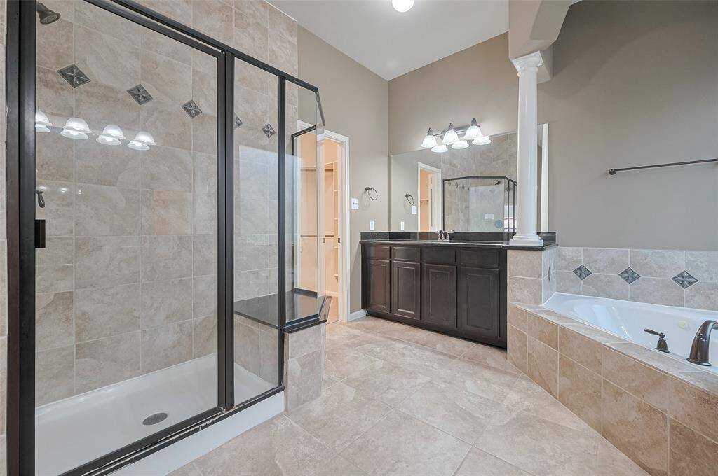 Split dual vanities, separate shower and soaking tub, tasteful tile and wood finishes