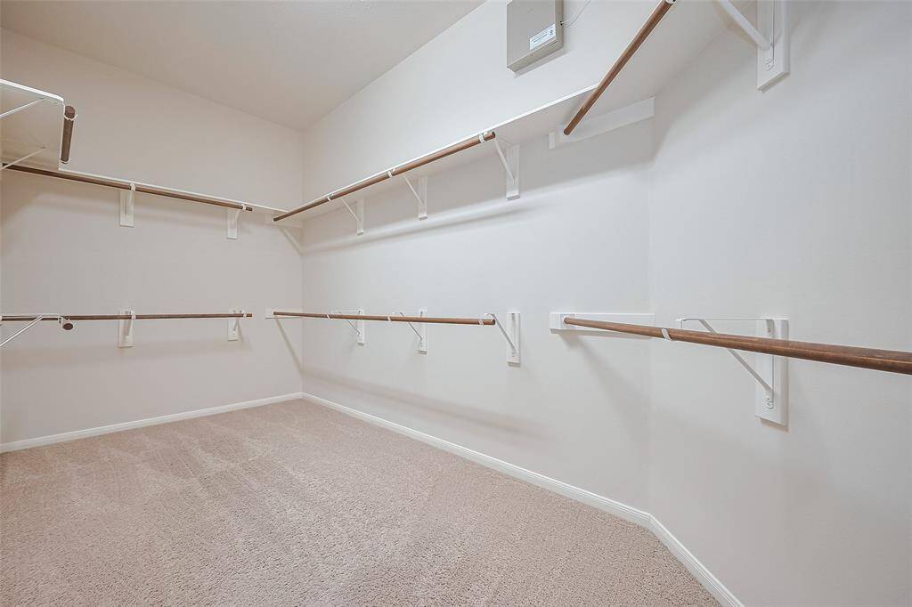 Massive primary walk-in closet with built-in shelving, double hung clothing racks and so much space!