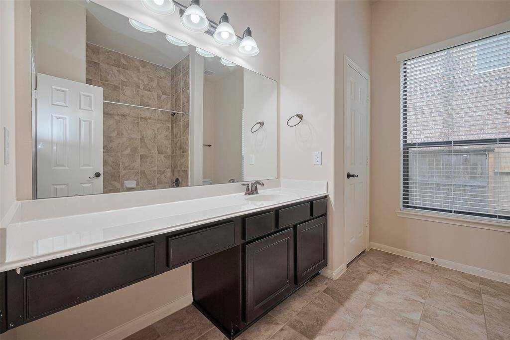 Dual sinks and framed mirror in secondary bathroom with ample counter space