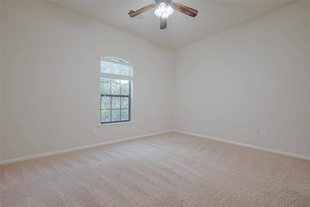 Bright secondary bedroom with large window and neutral tones, split floorplan in the home allows for guest privacy
