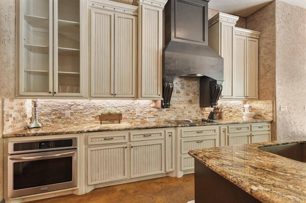 Stunning kitchen featuring elegant cabinetry, granite countertops, and a stylish backsplash.