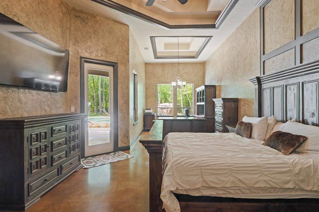 Luxurious primary bedroom featuring elegant tray ceilings, abundant natural light, and private patio access. A perfect blend of style and comfort awaits.
