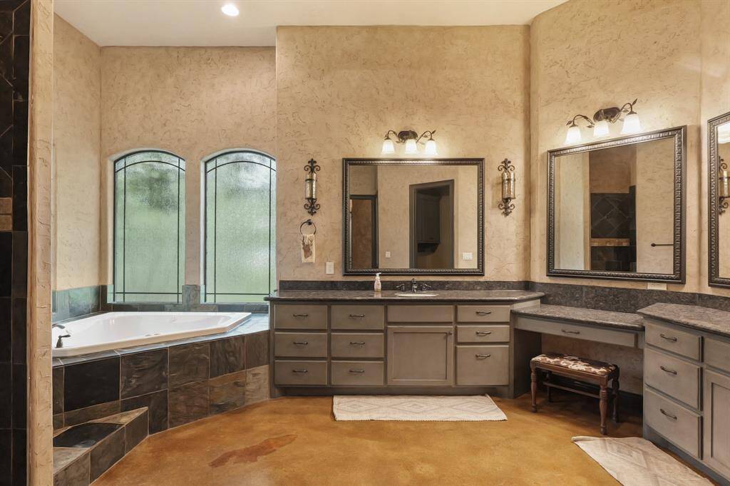 Luxurious primary bathroom featuring a jacuzzi, double sinks, and a spacious vanity.