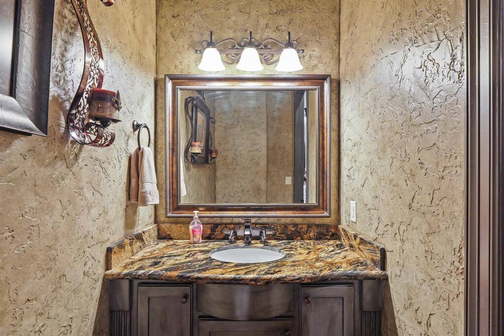 Elegant powder room with a stylish vanity and warm, textured walls. Perfect for guests.