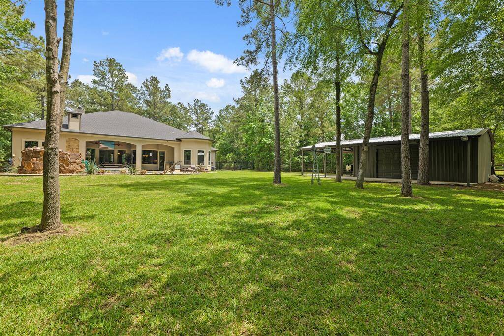 Charming backyard view featuring a spacious home and versatile barn/workshop, set against a lush, wooded backdrop.