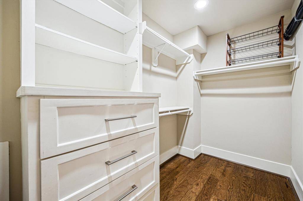 The walk in primary closet with shelving options and a built-in dresser.
