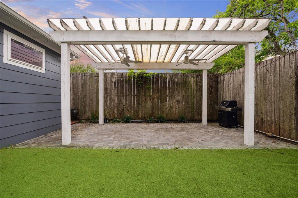 The covered pergola is at the rear of the yard. Thegarage is the wall seen here. Pavers make this a great spot for patio furnitureand the extra tall fence allows for ample privacy.