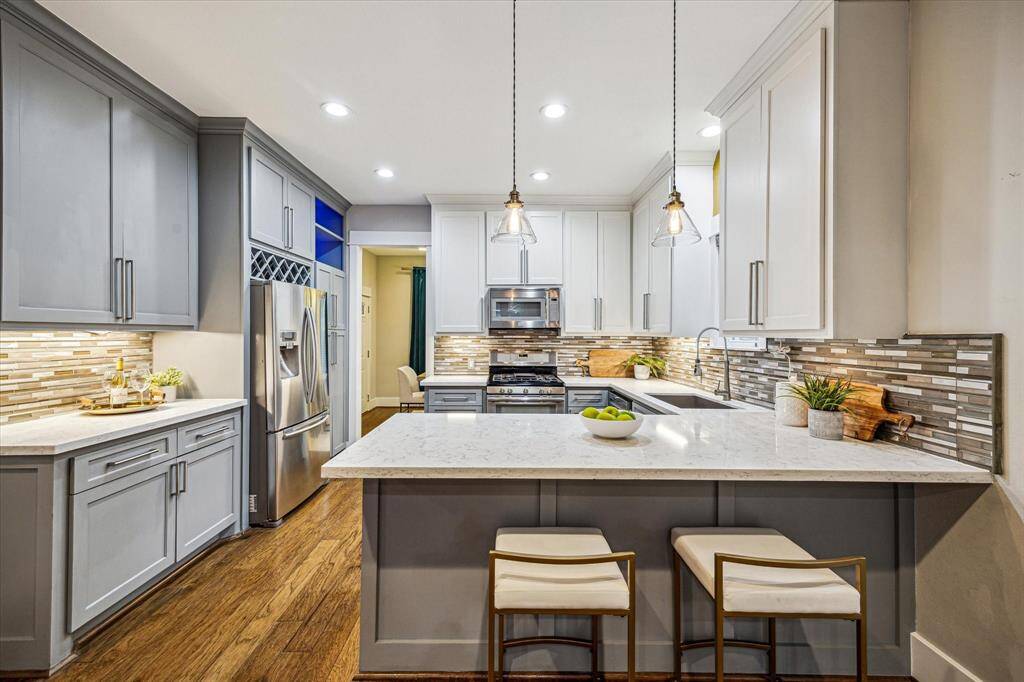 This chef's kitchen has all you need with white andgrey cabinetry, stainless steel appliances, a mosaictile backsplash, and a breakfast bar. There is pantystorage to the right of the refrigerator andimmediate access to the formal dining room at theback of the house.