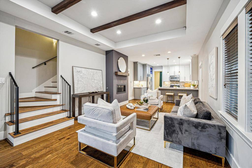This open-plan living space on the first floorfeatures high ceilings with exposed beams,hardwood floors, a staircase with a sleek blackrailing, and large windows allowing for plenty ofnatural light. The area seamlessly connects to anadjoining kitchen and dining room, creating anexpansive feel ideal for entertaining or casualliving.