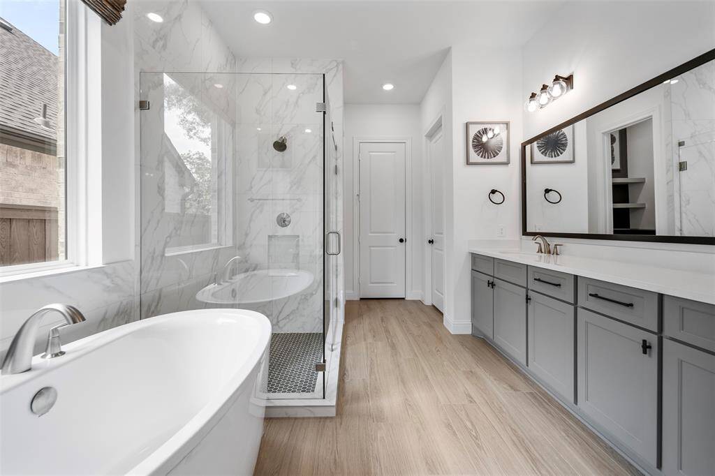 The ensuite bath exudes a spa-like ambiance with sleek features, luxurious soaking tub, a walk in shower, and dual sinks.