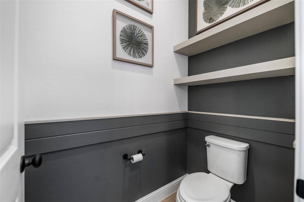 The toilet has its own enclosure in the primary bath with added shelving for stylish decor or personal belongings.