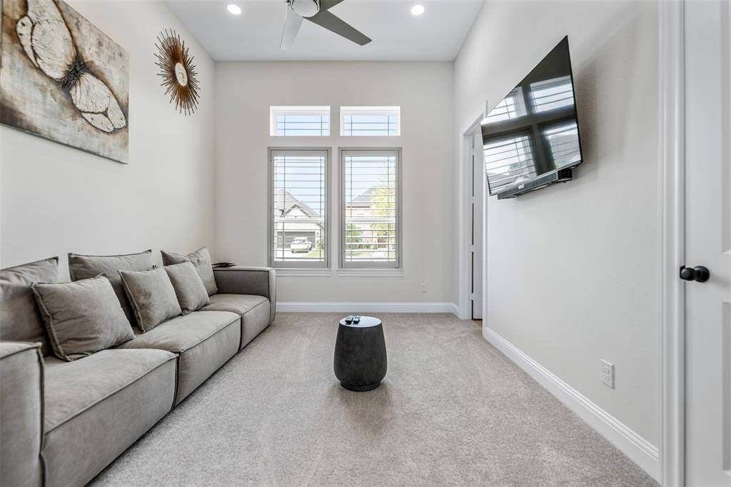 The secondary bedroom is bright and inviting, featuring large front-facing windows that flood the space with natural light. A sleek ceiling fan adds a modern touch and an ensuite bath makes the room perfect for children or guests.