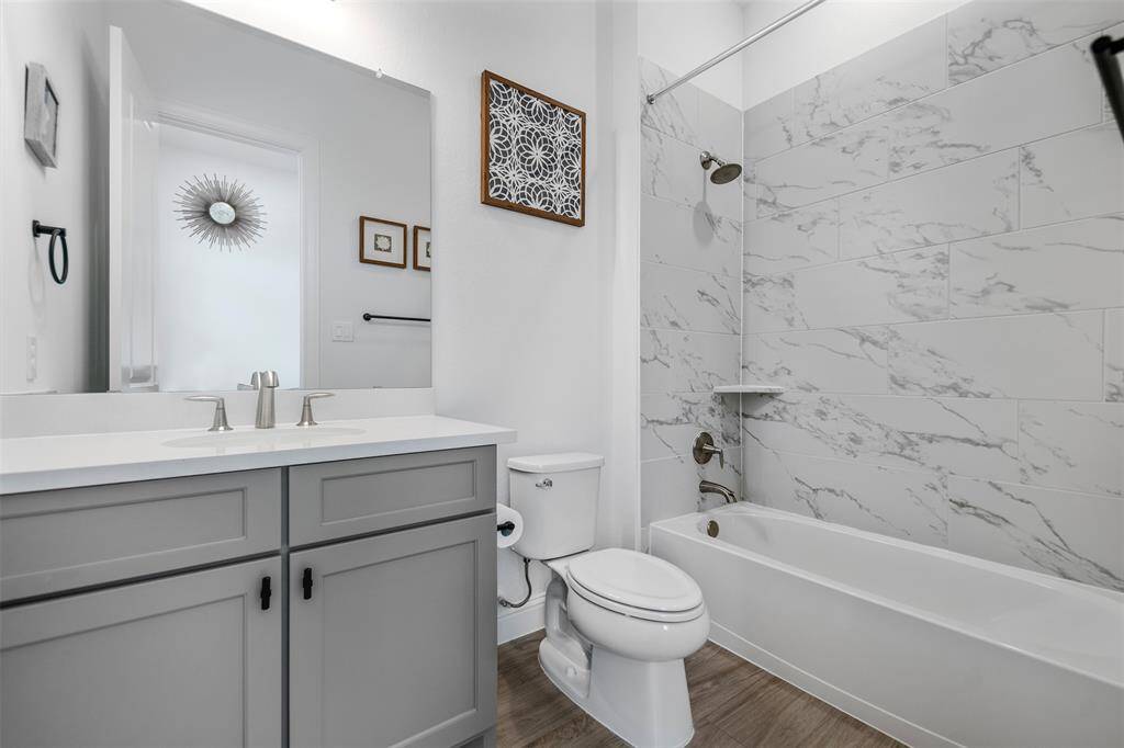 The third full bath features stylish wood-like flooring and a calming grey color palette, creating a modern yet serene atmosphere. The tub-shower combo offers both convenience and comfort, making this bath a perfect blend of function and design.