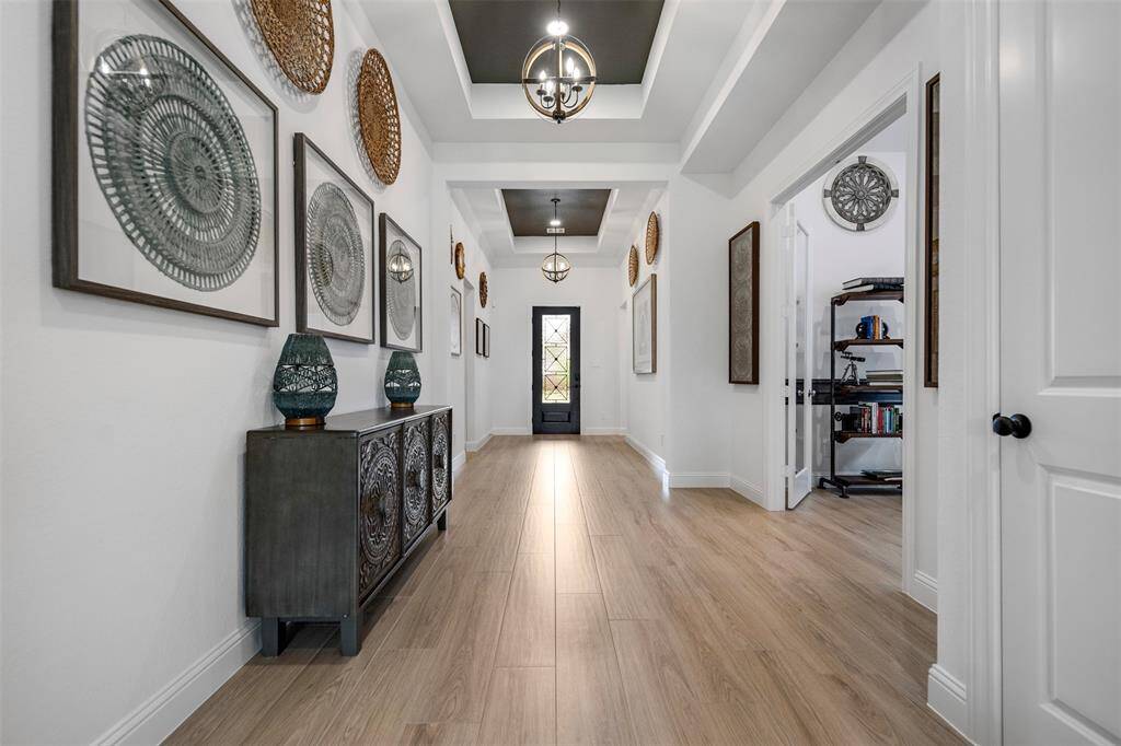 Step into elegance with this stunning formal entryway, where soaring ceilings, gleaming floors, and abundant natural light create a grand first impression. A statement chandelier casts a warm glow over the space, while detailed molding and architectural touches set the tone for the sophistication found throughout the home.