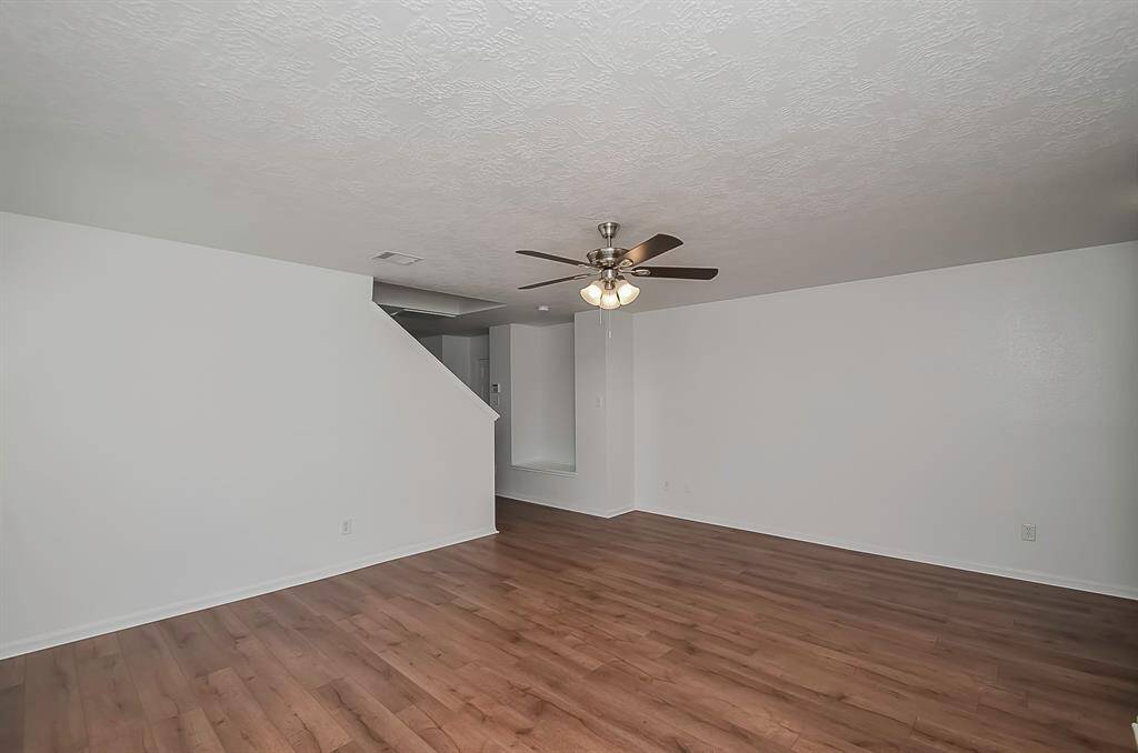The spacious living room offers open views, accentuated by the seamless flow of colors that beautifully complement the wood flooring throughout both downstairs and upstairs. The freshly painted white tone paint adds to the overall brightness and charm of the space.