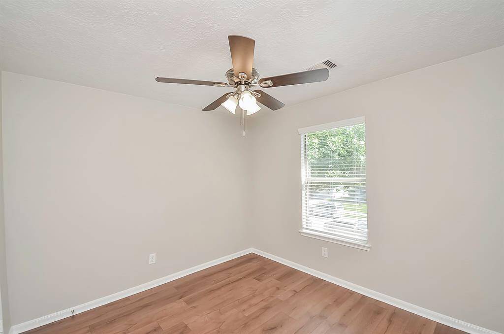 This is one of the three bedrooms, boasting ample closet space, a ceiling fan, and coordinated window treatments. The same LVP flooring adds to the consistent aesthetic, and it's conveniently situated next to the guest bathroom.