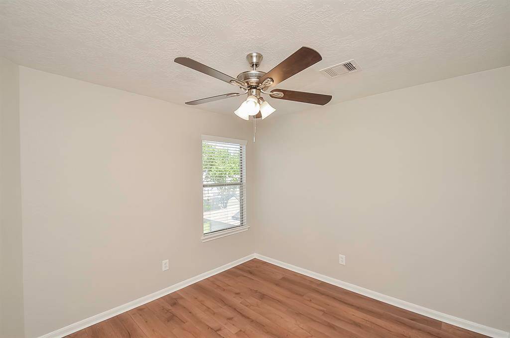 This is one of the three bedrooms, boasting ample closet space, a ceiling fan, and coordinated window treatments. The same LVP flooring adds to the consistent aesthetic, and it's conveniently situated next to the guest bathroom.