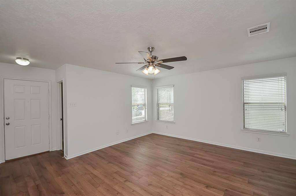 A view to the front door, to the right, leading to the powder room. Notice the high ceilings throughout, with ceiling fans in every room. The LVP flooring and fresh paint further enhance the ambiance.